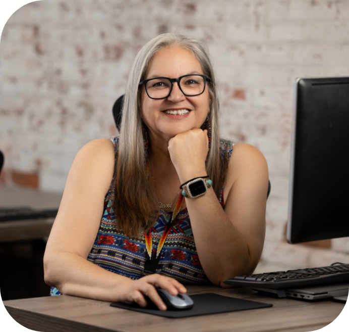 Tribal partner sitting in a desk smiling.